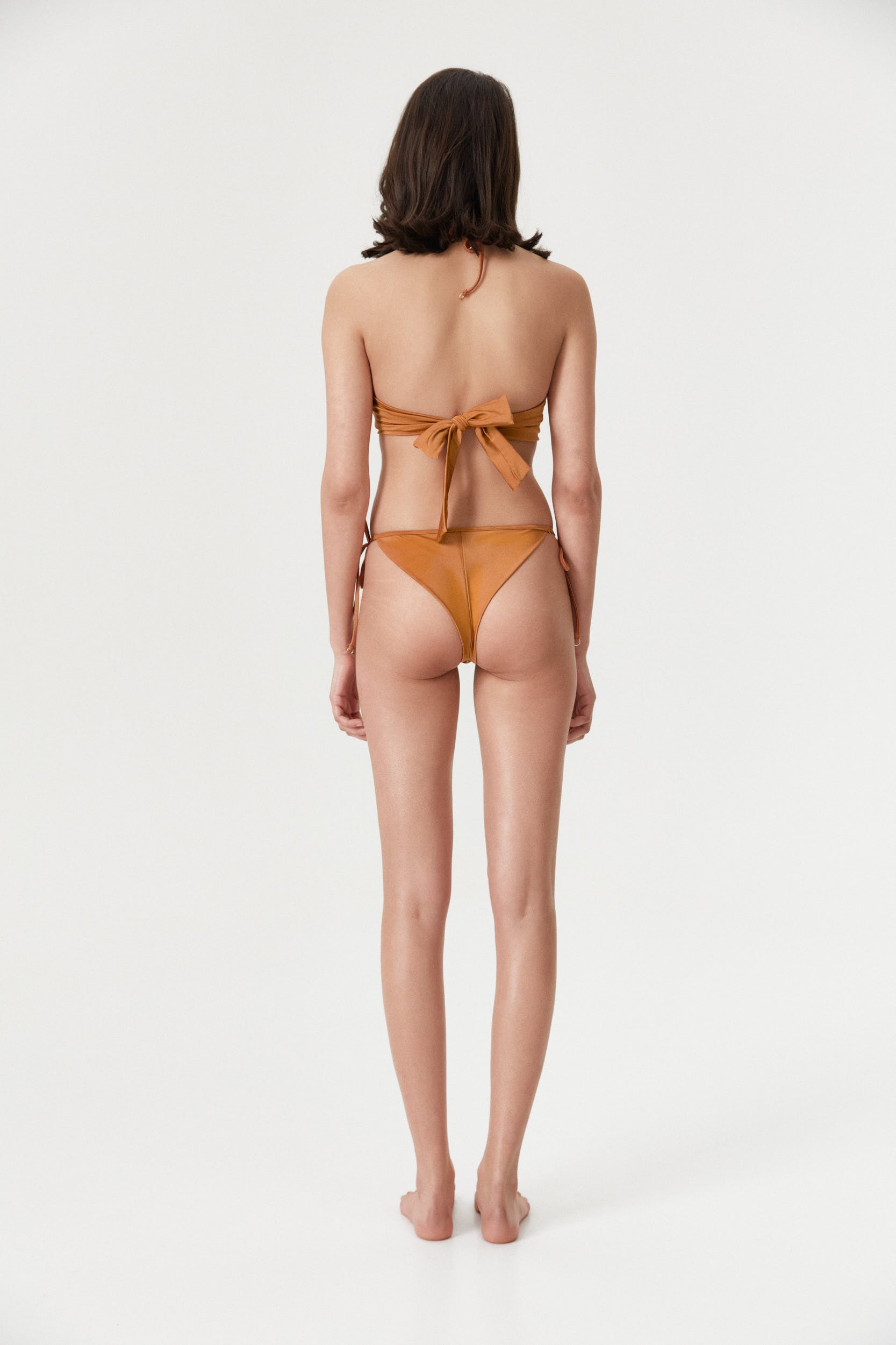 Back view of a female model wearing the Amber Brazilian Tie Side Bottom, showcasing its adjustable side ties and vibrant amber color.