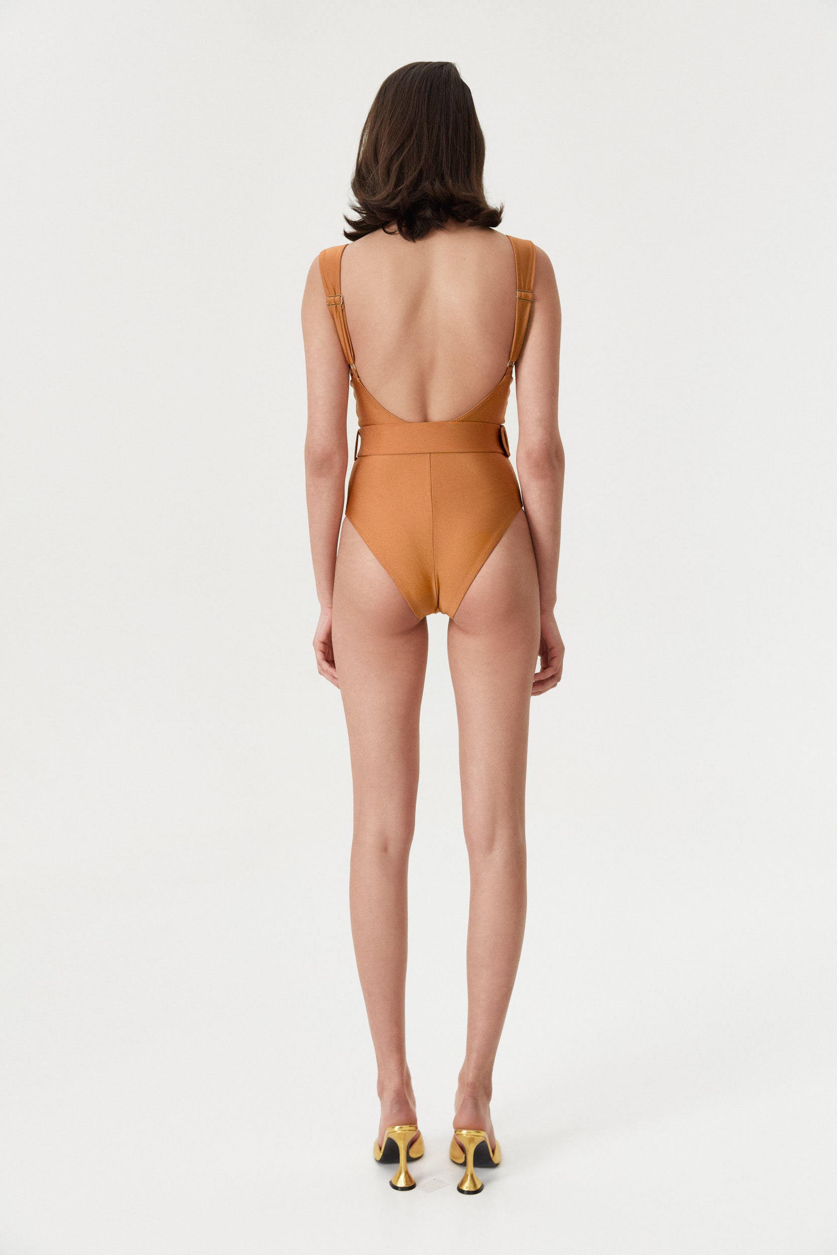 Back view of a female model wearing the Amber Iconic One Piece, showcasing its elegant design in vibrant amber color.